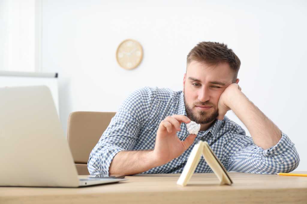Lazy young male office employee procrastinating at workplace